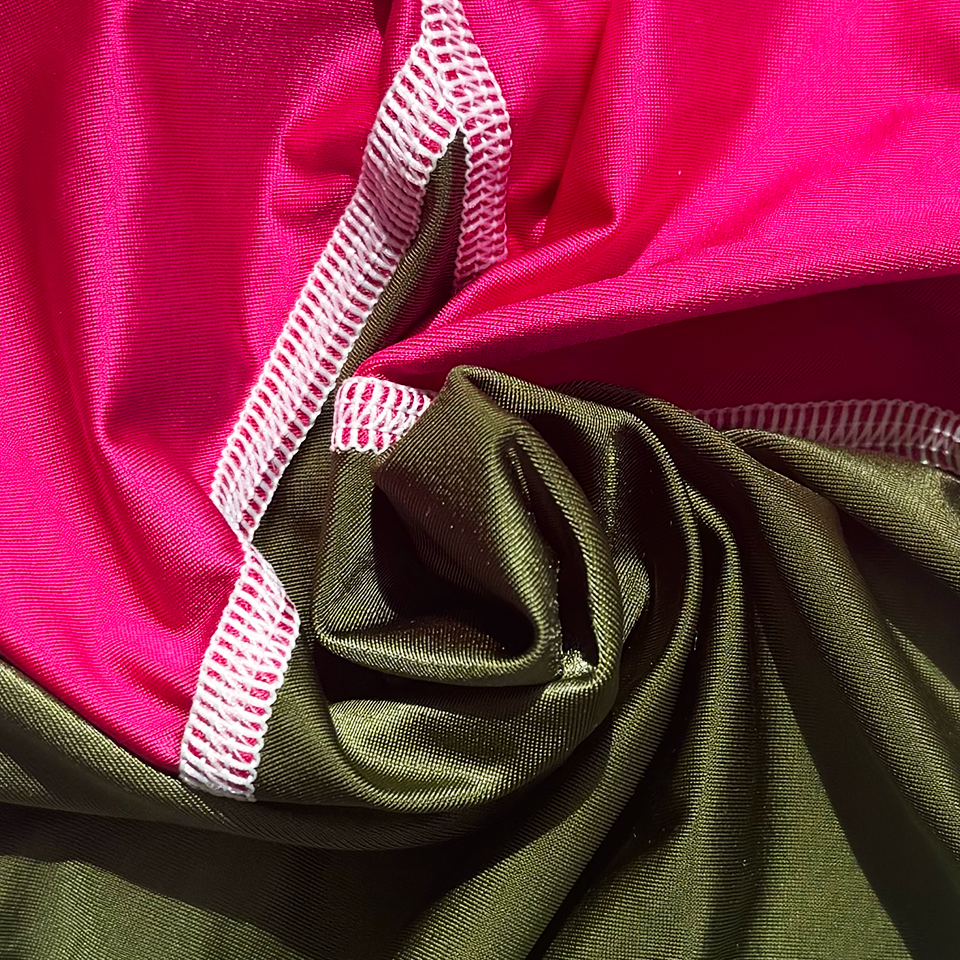 Close-up of pink and green lycra with white stitching.