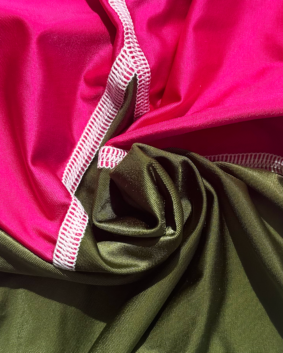 Close-up of pink and green lycra with white stitching.