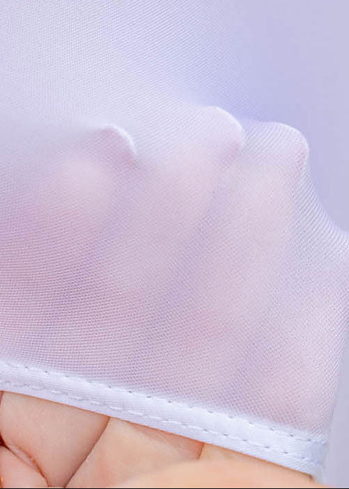 Close-up of a white lace doily held by a hand against a light purple background