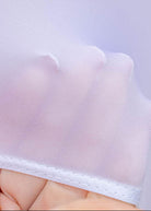 Close-up of a white lace doily held by a hand against a light purple background