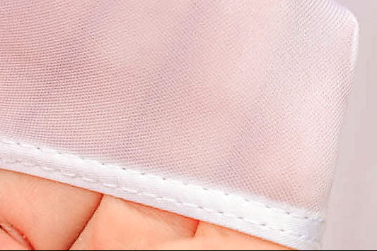 Close-up of a white mesh fabric held by a hand against a light background