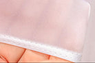Close-up of a white mesh fabric held by a hand against a light background